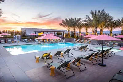 a resort pool with chairs and umbrellas at sunset at Noho Alexan Modern 2bed Duo with FREE Parking in Garnsey