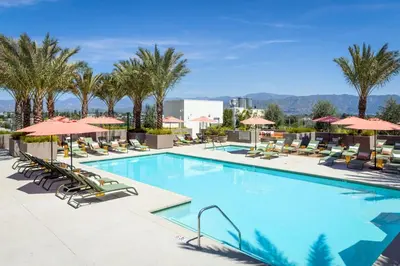 a pool with chairs and umbrellas at a hotel at Noho Alexan Modern 2bed Duo with FREE Parking in Garnsey