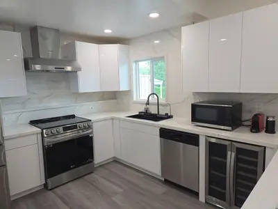 a kitchen with white cabinets and a black stove top oven at Soft elegance, modern guest house in Alhambra