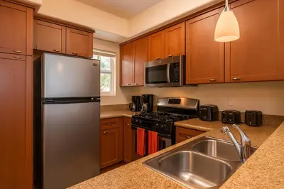 a kitchen with wooden cabinets and a stainless steel refrigerator at Marina Del Rey Sunrise - Pool & Gym & Sauna & Cinema in Marina del Rey