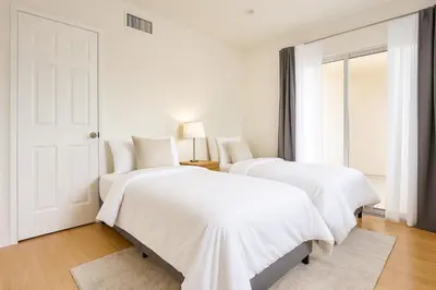 two beds in a white room with a door at Malibu Woods & Waves - 2 Bedroom in Malibu