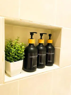 four bottles of wine on a shelf in a bathroom at Stylish 3BR Getaway plus Pool in Tarzana