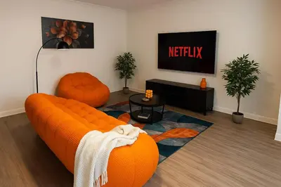 a living room with an orange couch and a tv at Modern Comfort near Universal in Los Angeles