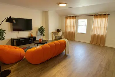 a living room with orange furniture and a flat screen tv at Modern Comfort near Universal in Los Angeles