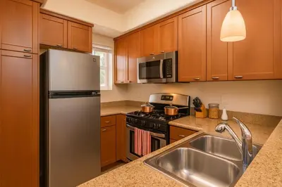 a kitchen with wooden cabinets and a stainless steel refrigerator at Marina Del Rey Luxe 2-Bedroom & 1-Bedroom - Hot Tub, Pool Table, Grill & Cinema Projector in Marina del Rey