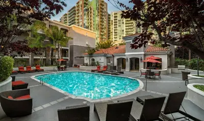 a swimming pool with chairs and a building at Sunny Marina Del Rey Apartment- Hot Tub, Game Room, BBQ, Projector in Los Angeles