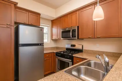 a kitchen with wooden cabinets and a stainless steel refrigerator at Sunny Marina Del Rey Apartment- Hot Tub, Game Room, BBQ, Projector in Los Angeles