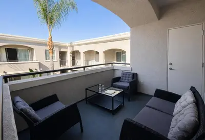 a balcony with couches and a table and a palm tree at Chic Marina 1 Bedroom - Pool - Hot Tub - Gym - Sauna in Los Angeles