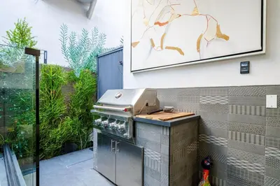 a grill in a patio with a picture on the wall at Venice House w Pool Spa Home Theater Rooftop in Los Angeles