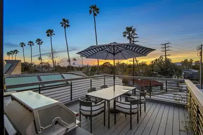 a patio with a table and chairs and an umbrella at Venice House w Pool Spa Home Theater Rooftop in Los Angeles