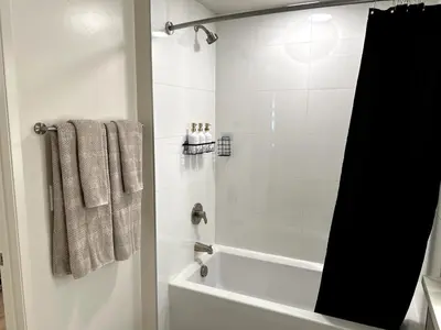 a bathroom with a tub and a shower with towels at Cozy studio in heart of Santa Monica free parking in Los Angeles