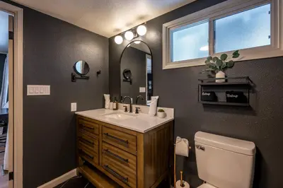a bathroom with a sink and a toilet and a mirror at Summit Haven: Game Room | Sauna | Spa | 1/4 Acre in Big Bear Lake