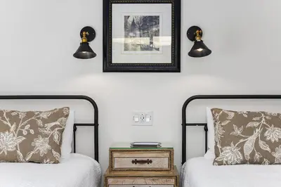 two beds in a room with two lamps and a night stand at The Petite-Villas at Dorner Family Vineyard in Tehachapi