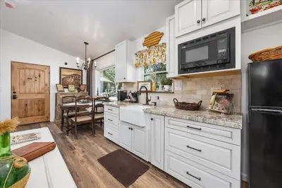 a kitchen with white cabinets and a black refrigerator at The Petite-Villas at Dorner Family Vineyard in Tehachapi