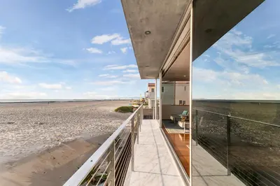 a beach house with a balcony looking out at the beach at ocean front beach house in Oxnard