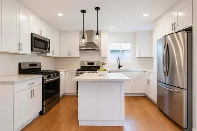a kitchen with white cabinets and a stainless steel refrigerator at Fullerton Family-Ready- 9 min to Disneyland in Fullerton
