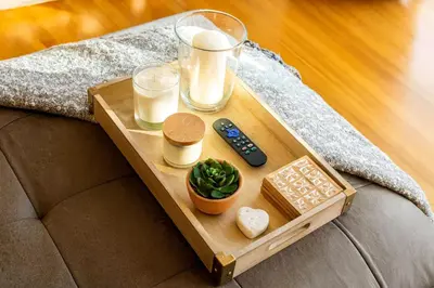 a tray on a couch with a remote control and candles at 4BR Fullerton Retreat - Private Backyard in Fullerton