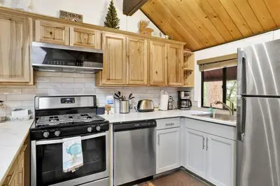 a kitchen with stainless steel appliances and wooden cabinets at Switzerland Summit Condo- Cozy Base Camp Resort Chalet- Walk to Ski Lifts + Hiking in Big Bear Lake