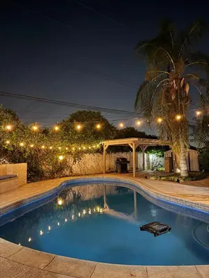 a swimming pool in a backyard at night with lights at The Maze House Pool Theatre Room in San Bernardino
