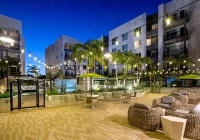 a courtyard in a building with chairs and umbrellas at Pacific Paradise 10 Min from Disneyland With Pool & GYM in Santa Ana
