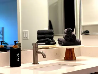 a bathroom sink with a stack of towels in front of a mirror at Luxury Haven 10 Min From Disneyland With Pool & GYM in Santa Ana