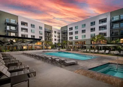 a swimming pool with chairs and a building at Modern Retreat 10 Min from Disneyland With Pool & Gym in Santa Ana