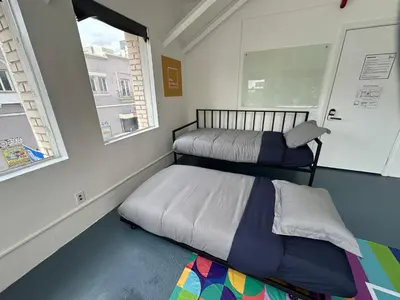 two beds in a room with two windows at The Art Nook Private Rooms on Hollywood Blvd in Los Angeles