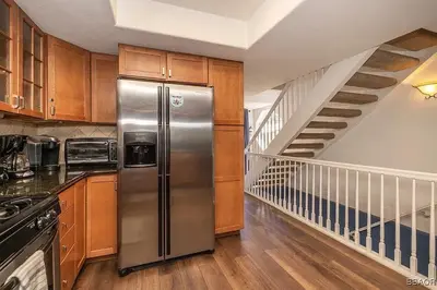 a kitchen with a stainless steel refrigerator and a staircase at Lake Forest Shores at Big Bear Lake in Big Bear Lake
