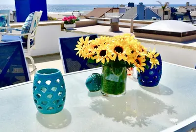 a vase with yellow flowers on a table with two blue vases at Luxury, Beach House, and quiet neighborhood in Oxnard