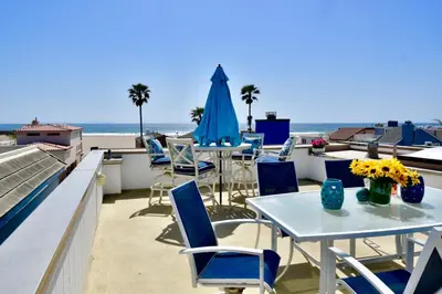 a patio with tables and chairs and the ocean at Luxury, Beach House, and quiet neighborhood in Oxnard