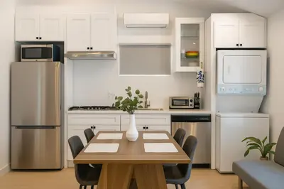 a kitchen with white cabinets and a wooden table with chairs at South Pasadena Studio Spa Escape in South Pasadena