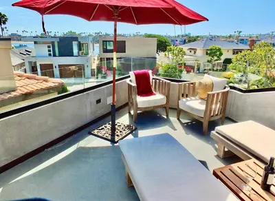 a patio with a red umbrella on a roof at Naples Luxury Retreat - 3 BDR Stay for 6 w Rooftop Patio in Long Beach