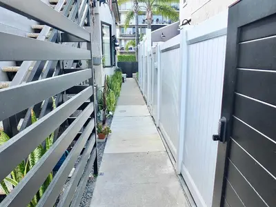 a fence and a sidewalk next to a white fence at Naples Luxury Retreat - 3 BDR Stay for 6 w Rooftop Patio in Long Beach