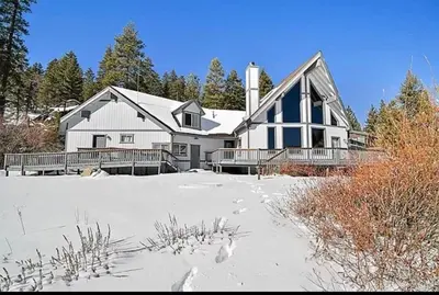 a large white house in the snow with trees at Lakefront Oasis in Fawnskin