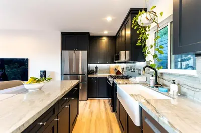 a kitchen with black cabinets and white counter tops at Hidden Oasis 3 bedroom 2 bathroom Home With large backyard and Views Near DTLA in Los Angeles