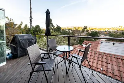 a balcony with chairs and a table and an umbrella at Hidden Oasis 3 bedroom 2 bathroom Home With large backyard and Views Near DTLA in Los Angeles