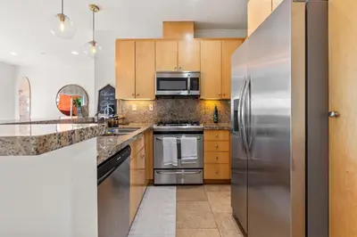 a kitchen with stainless steel appliances and wooden cabinets at Ocean View condo in the heart of Manhattan Beach in Manhattan Beach