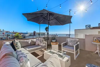 a patio with a couch and an umbrella on a roof at Ocean View condo in the heart of Manhattan Beach in Manhattan Beach
