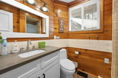a bathroom with a toilet and a sink and a mirror at Navigate Stays 5BR Group Lodge Near Mountain & Fun in Big Bear Lake