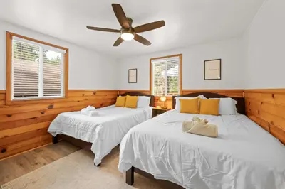 two beds in a room with a ceiling fan at Navigate Stays 5BR Group Lodge Near Mountain & Fun in Big Bear Lake