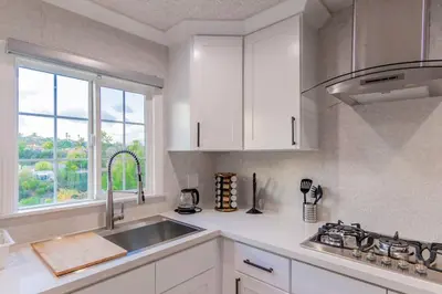 a kitchen with white cabinets and a sink and a window at Cozy Comfort LA House with Stunning Scenic Views in Monterey Park