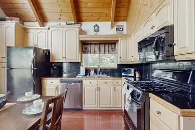 a kitchen with white cabinets and a table with chairs at Cedar Glen Hideaway in Lake Arrowhead