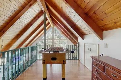 a room with a table and a balcony with wooden ceilings at Cedar Glen Hideaway in Lake Arrowhead