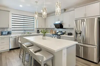 a large kitchen with a large white island with chairs at Modern Townhouse Near Disneyland & OC Beaches in Covina