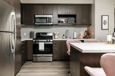 a kitchen with stainless steel appliances and wooden cabinets at Elegant 2BD WeHo Apartment in Los Angeles