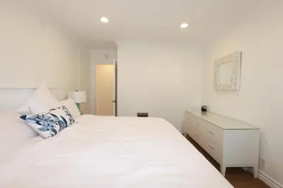 a white bedroom with a white bed and a dresser at SM ocean view in Los Angeles