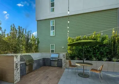 a patio with a table and an umbrella next to a building at Charming 2BR Retreat Pool Gym 10min to Disneyland in Santa Ana