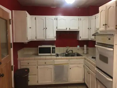 a kitchen with white cabinets and a sink and a microwave at Affordable Rooms in RV Trailer in Los Angeles