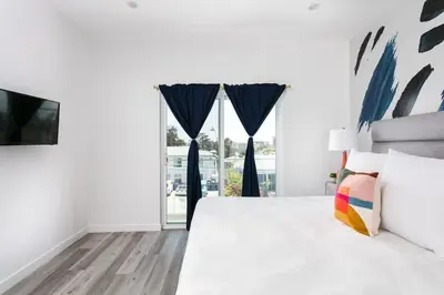 a white bedroom with a large bed and a window at Upscale LA Getaway Sleeps 8 with Free Parking in Los Angeles