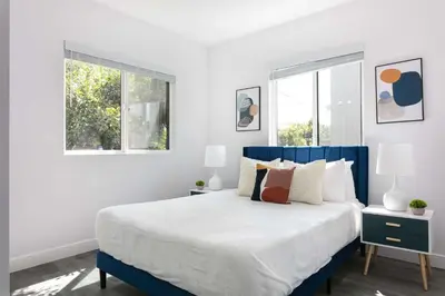 a bedroom with a blue and white bed with two windows at Spacious 5BR Townhouse with Free Parking Included in Los Angeles